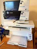 HP LaserJet printer with two 17A toner cartridge boxes stacked on top