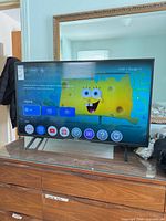 Front view of Sony smart TV powered on, showing size and stand