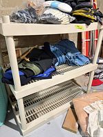 Full view of beige plastic three-shelf unit with items placed on top for scale