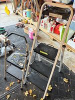 Two folding ladders standing side by side showing size difference and steps