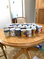 Group view of all ceramic mugs arranged on round wooden table