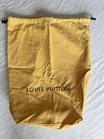 Front view of tan Louis Vuitton dust bag with logo showing