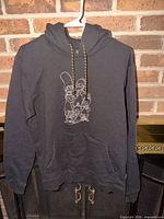 Full view of black Billabong × The Simpsons hoodie on hanger