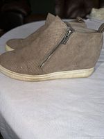 Side view showing suede upper, perforations, side zipper, wedge heel