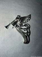 Front view of silver-tone angel brooch pin on fabric background