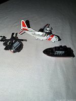 Three toy vehicles laid out: airplane, helicopter, boat