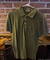 Front view of army green Penguin polo on hanger showing entire shirt