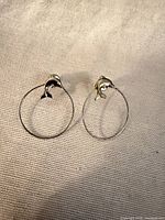 Front view showing both dolphin hoop earrings on neutral fabric background