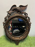 Front view of round mirror with eagle crest and scroll frame
