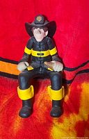 Front view of resin firefighter shelf sitter figurine showing uniform and seated pose