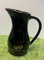 Left profile of black ceramic Johnnie Walker pitcher showing shape and gold rim