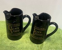 Front view of both black ceramic Black Velvet pitchers showing branding