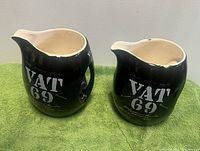 Front view of both black VAT 69 ceramic pitchers showing logos and overall shape