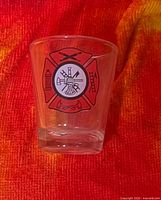 Front view of shot glass showing firefighter Maltese cross emblem
