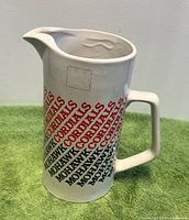 Front view of white ceramic Mohawk Cordials pitcher showing graphics and spout