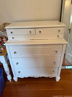 Front view of white 5-drawer dresser with glass knobs