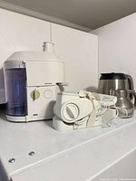 Braun juicer, Deni cheese grater, stainless steel kettle grouped on shelf