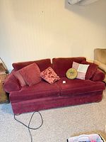 Front view of burgundy fabric sofa bed with five cushions
