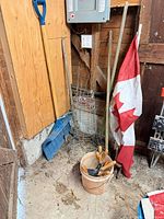 Overall view: snow shovel, plant cages, flag, pail with hand tools