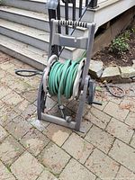 Full view of gray plastic HoseMobile reel cart with green hose and crank