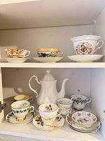 Cabinet shelf showing teapot, multiple teacups and saucers