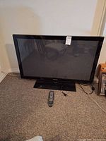 Front view of Samsung plasma TV on stand with remote and power cable