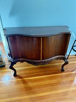Full view of wood sideboard showing serpentine top, curved doors, carved legs
