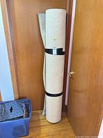 Rolled beige rug secured with straps standing upright