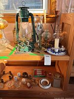 Overall view of lantern, chimneys, various candle holders, boxed items on shelves