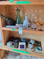 Wide view of shelf showing barware, pottery and coasters