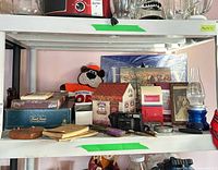Shelf view with camera, Trivial Pursuit box, keepsake boxes, plush bear, oil lamp and paper items