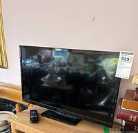Front view of Insignia 24-inch LED TV on stand with remote placed on table