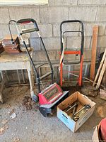 Snow thrower, dolly and box of light stakes grouped in garage