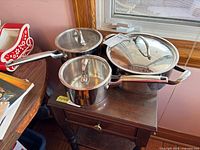 Three stainless steel Paderno pots with lids displayed on table