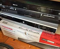 Front view of stacked Toshiba DR430, SD-V395, D-R5 units and boxed 1080p up-conversion recorder