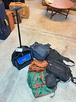 Overview of all seven bags on floor, including rolling trolley, messenger, laptop bag, handbag, duffel, backpack and pouch