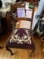 Front view showing carved wood frame and needlepoint seat