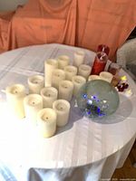 Group of ivory pillar candles, lighted glass globe, red candles, jar candle, tealights