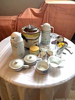 Overall view of crock-pot, thermoses, clock and assorted tableware on round table