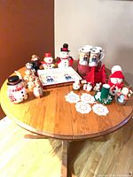 All items arranged on round table showing cookie jar, platter set, mugs, figurines and decorations