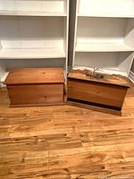 Both wooden trunks closed, side by side on floor