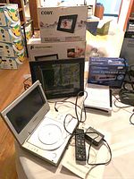 Group shot showing open Curtis DVD player, remote, manuals, Winegard converter box, digital photo frame boxes