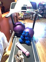 Treadmill belt area holding exercise balls, dumbbells, yoga mat, roller skates