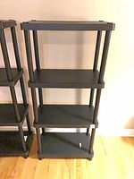 Front view of black plastic 4-tier shelving unit