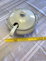 Tureen with lid and ladle beside measuring tape showing size