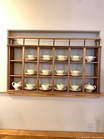Front view of wall-mounted solid wood display shelf showing 12 cubbies and top spindle rail.