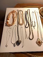 Board with multiple necklaces including peach beads, assorted chains, heart pendants