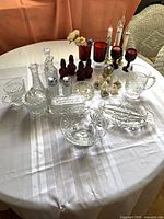Full view of table with clear Wexford glassware, red glass pieces, perfume bottles and electric candlesticks