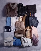 Overview of all folded garments showing mix of jackets, sweaters, trousers