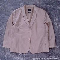Front view of tan blazer laid flat showing overall style and two-button closure
